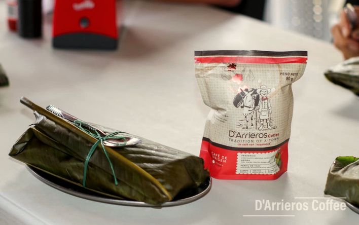 Fiambre envuelto en hoja de bijao junto a una bolsa de café